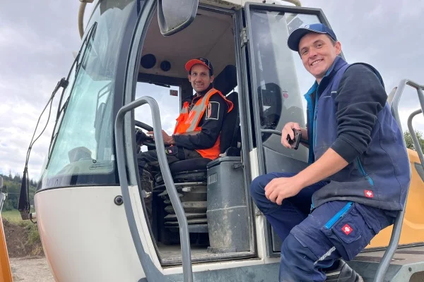 Das Bild zeigt zwei Männer mit einem Bagger