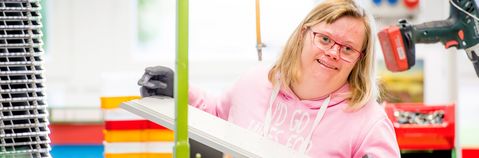 Das Bild zeigt eine junge Frau bei der Arbeit in einer Werkstatt