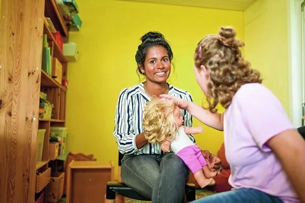 Auf dem Bild sieht man zwei Frauen und eine von ihnen hält eine Puppe in der Hand