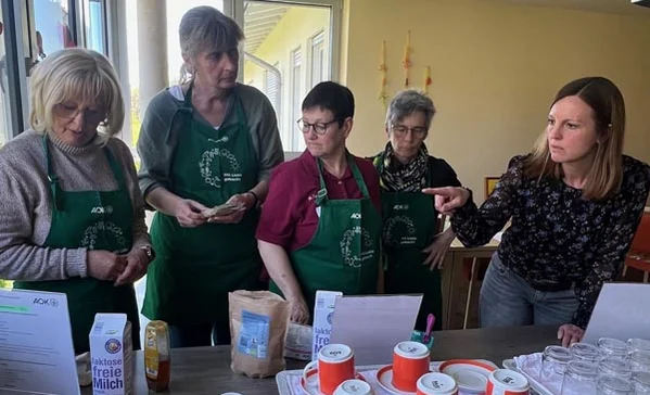 Mehrere Personen stehen an einem Tisch und besprechen etwas.