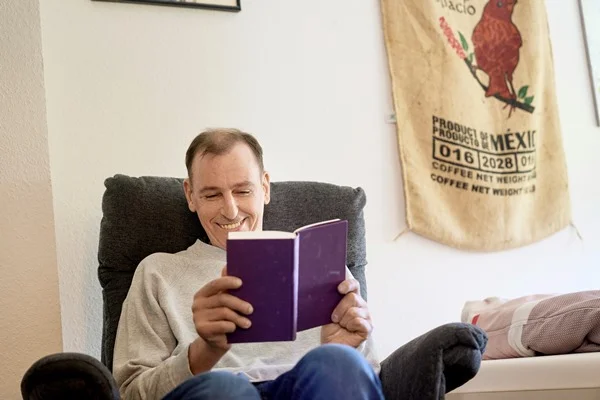 Das Bild zeigt eine Person in einem Sessel, lesend