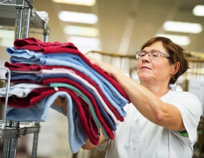 Das Bild zeigt eine Frau mit zusammengelegter Wäsche