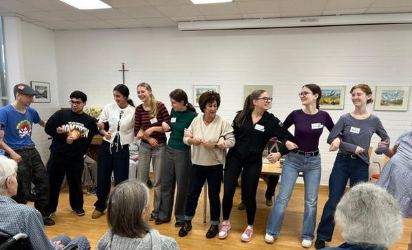 Das Bild zeigt eine Gruppe von Personen die alle aneinander gereiht sind und Tanzen 