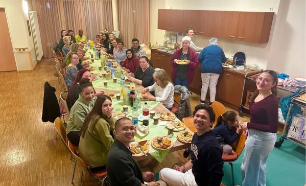 Eine Gruppe sitzt am Tisch und lächelt in die Kamera