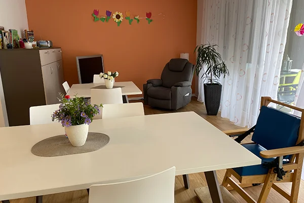 Das Bild zeigt eine Zimmereinrichtung mit Tisch, Stühlen und weiteren Möbeln