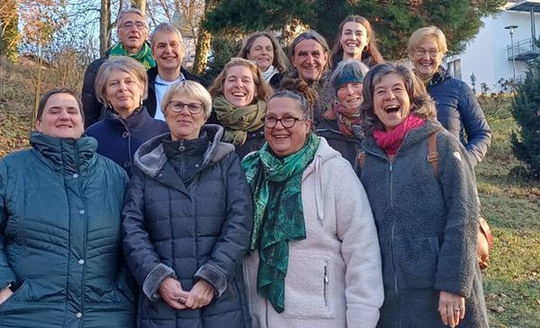 Das Bild zeigt eine Gruppe von Personen, die alle in einem Wald stehen und in die Kamera lächeln.