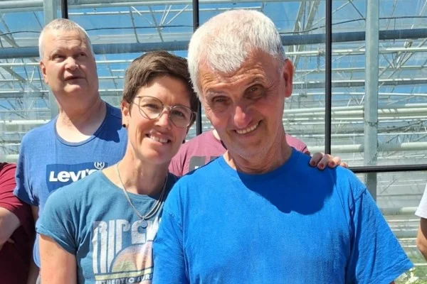 Das Bild zeigt zwei Männer und eine Frau vor einem Supermarkt