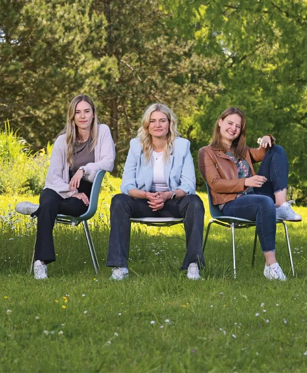 Drei Frauen sitzen auf verschiedene Weise auf Stühlen.
