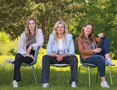 Drei Frauen sitzen auf verschiedene Weise auf Stühlen.