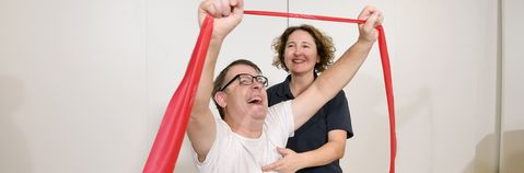 Das Bild zeigt zwei Frauen mit einem Theraband