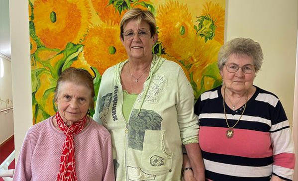 Drei Frauen stehen nebeneinander und schauen in die Kamera.