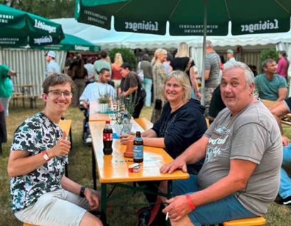 Das Bild zeigt mehrere Personene an einem Biergartentisch