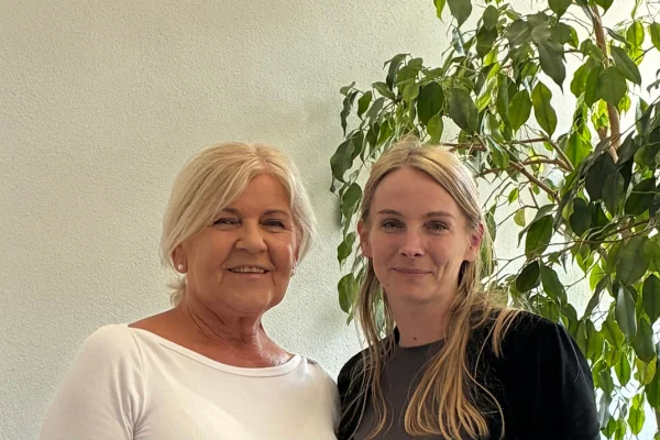 Zwei Frauen lächeln in die Kamera.