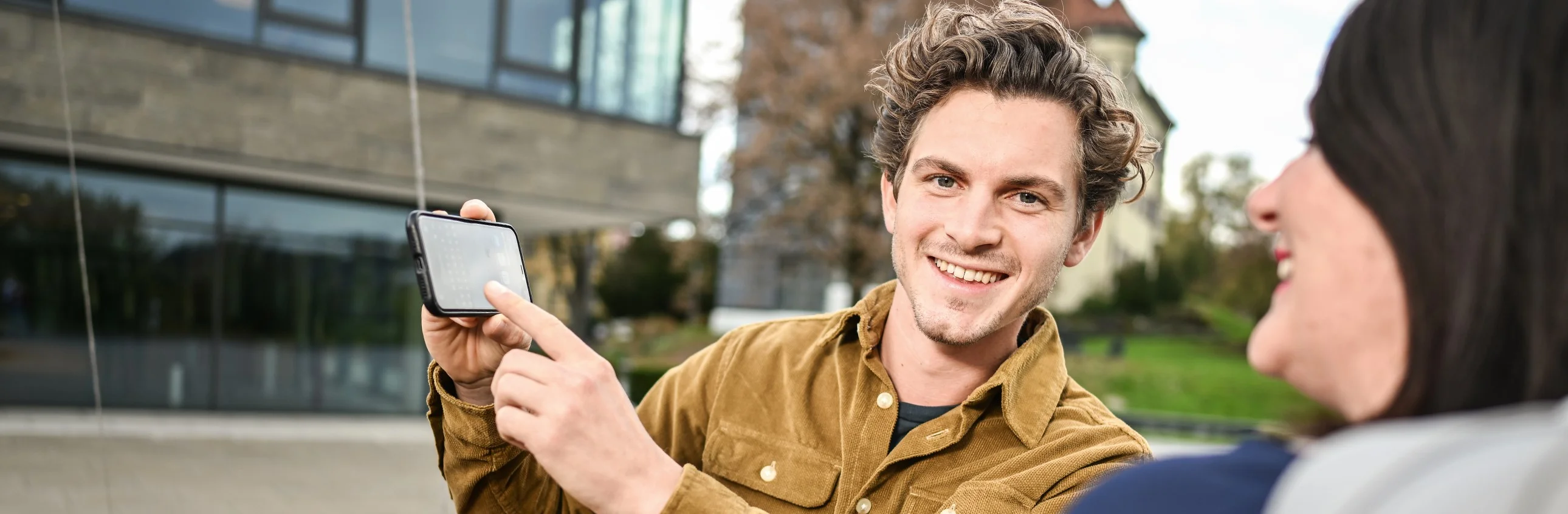 Das Bild zeigt einen jungen Mann und eine junge Frau mit Smartphone