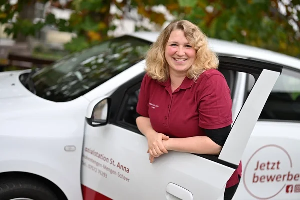 Das Bild zeigt eine Frau vor einem offenen Auto