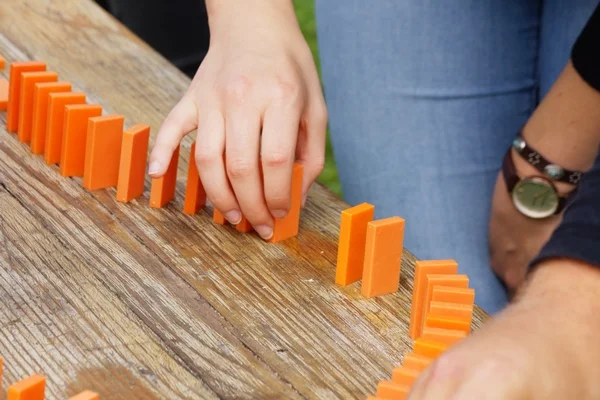 Auf dem Bild ist ein Dominosteinkette zu sehen die aus orangenen Steinen besteht.