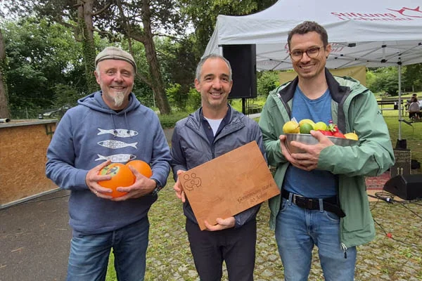 Drei Männer bei einem Gruppenfoto lächeln in die Kamera.