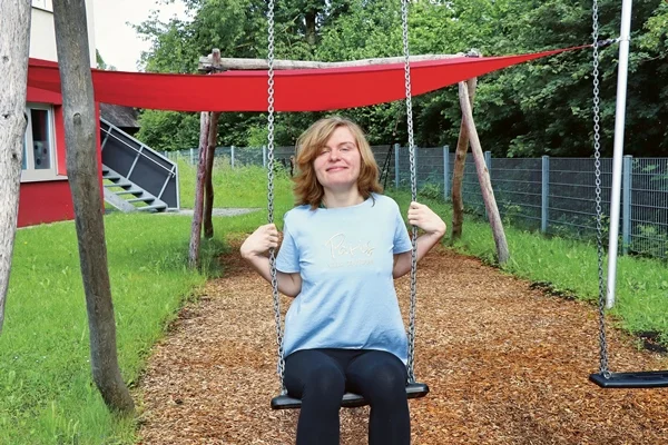 Seit über drei Jahren lebt Anne in dem sozialtherapeutischen Wohnheim „Leo 01” in Hegenberg Das Bild zeigt ein Mädchen das auf einer Schaukel sitzt und in die Kamera lacht