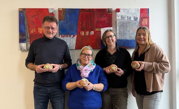 Vier Personen mit grünen Berlinern in der Hand.