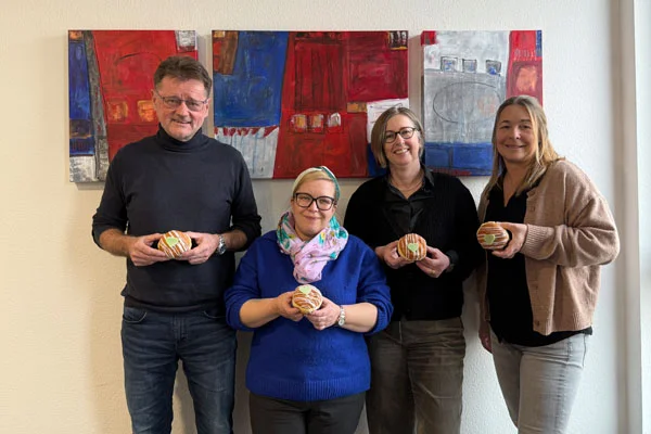 Vier Personen mit grünen Berlinern in der Hand.