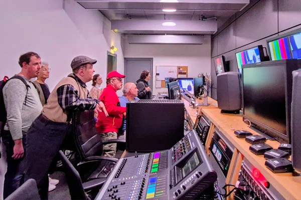 Einige Personen schauen im Aufnahmestudio auf Bildschirme.