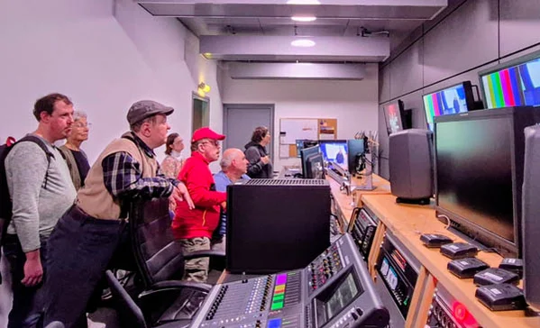Einige Personen schauen im Aufnahmestudio auf Bildschirme.