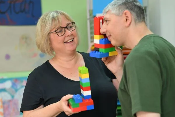 Auf dem Bild sieht man eine Frau und ein Mann die Bauklötze in der Hand halten