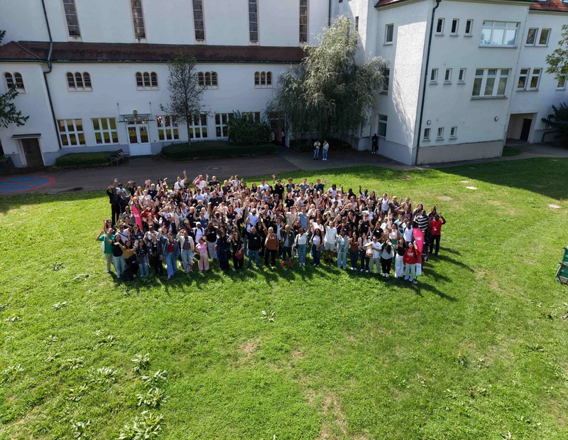 Einführungstag 2026 Gruppenbild als Drohnen Aufnahme auf einer Wiese.