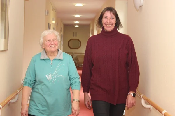 Manuela Beutling (links) engagiert sich ehrenamtlich im Haus der Pflege St. Leonhard in Isny. Einrichtungsleiterin Alexandra Greschla erlebt dies als große Bereicherung fürs ganze Haus. Das Bild zeigt zwei Personen die in Richtung der Kamera laufen