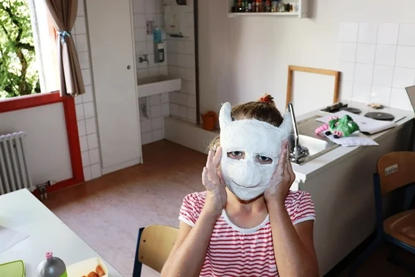 Das Bild zeigt ein Kind mit einer Maske aus Pappmachee