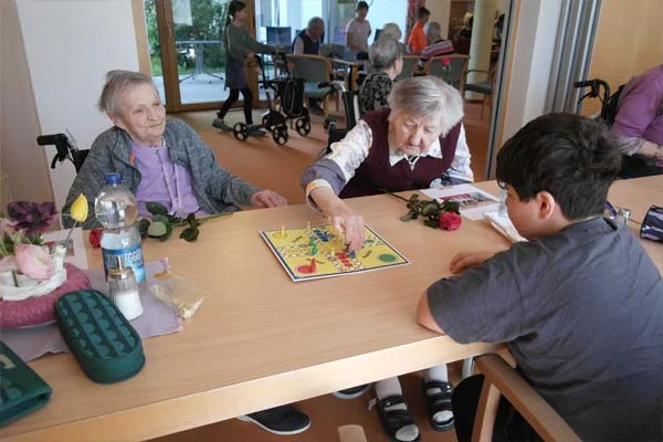 Kooperation Mehrere Personen sitzen an einem Tisch und spielen ein Brettspiel.