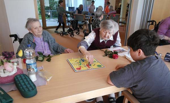 Mehrere Personen sitzen an einem Tisch und spielen ein Brettspiel.