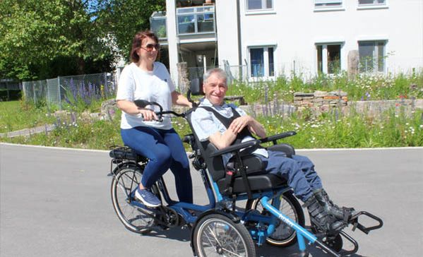 Das Foto zeigt Anja Rundel, Einrichtungsleitung Haus St. Raphael, und Karl Schlenska auf dem Rollstuhlfahrrad.