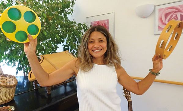 Eine Frau lacht in die Kamera und hält Instrumente in der Hand.