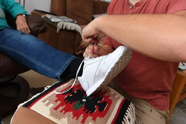 Das Bild zeigt Hände, die einen Schuh zubinden