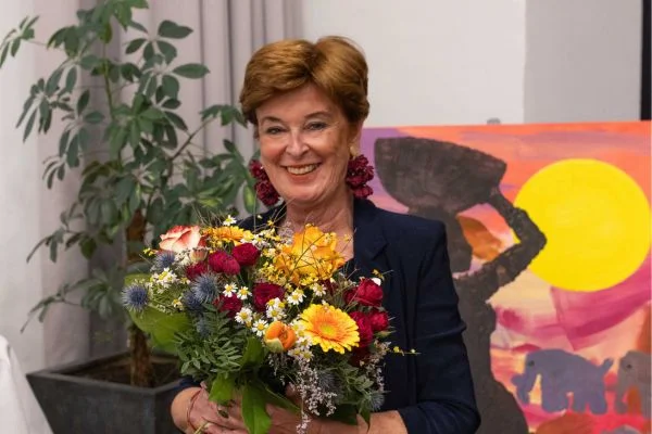 Ina Maria Lerchbaumer Eine Frau mit Blumenstrauß strahlt in die Kamera
