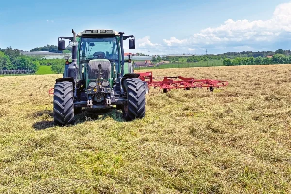 Das Bild zeigt einen Traktor der auf der Wiese fährt