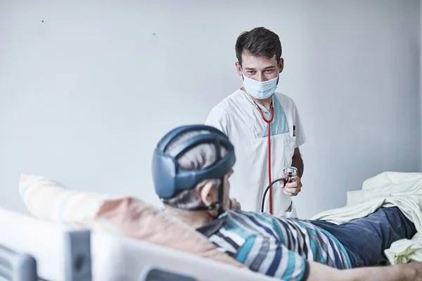 Auf dem Bild ist ein Doktor zu sehen, der gerade eine Untersuchung an einem Patienten durchführt.