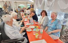 Mehrere Personen sitzen an einem Tisch in einem Festzelt.