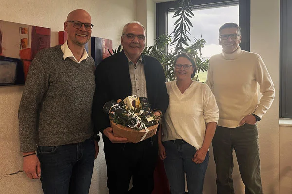 Vier Personen lächeln für ein Gruppenbild in die Kamera.