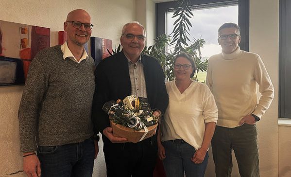 Vier Personen lächeln für ein Gruppenbild in die Kamera.