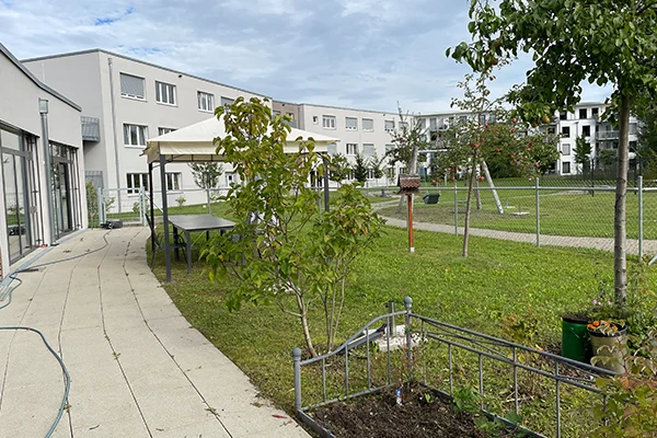Gemeindeintegriertes Wohnen und Fördern Singen Das Bild zeigt einen Innengarten mit bogenförmig darumherum angeordneten Gebäuden