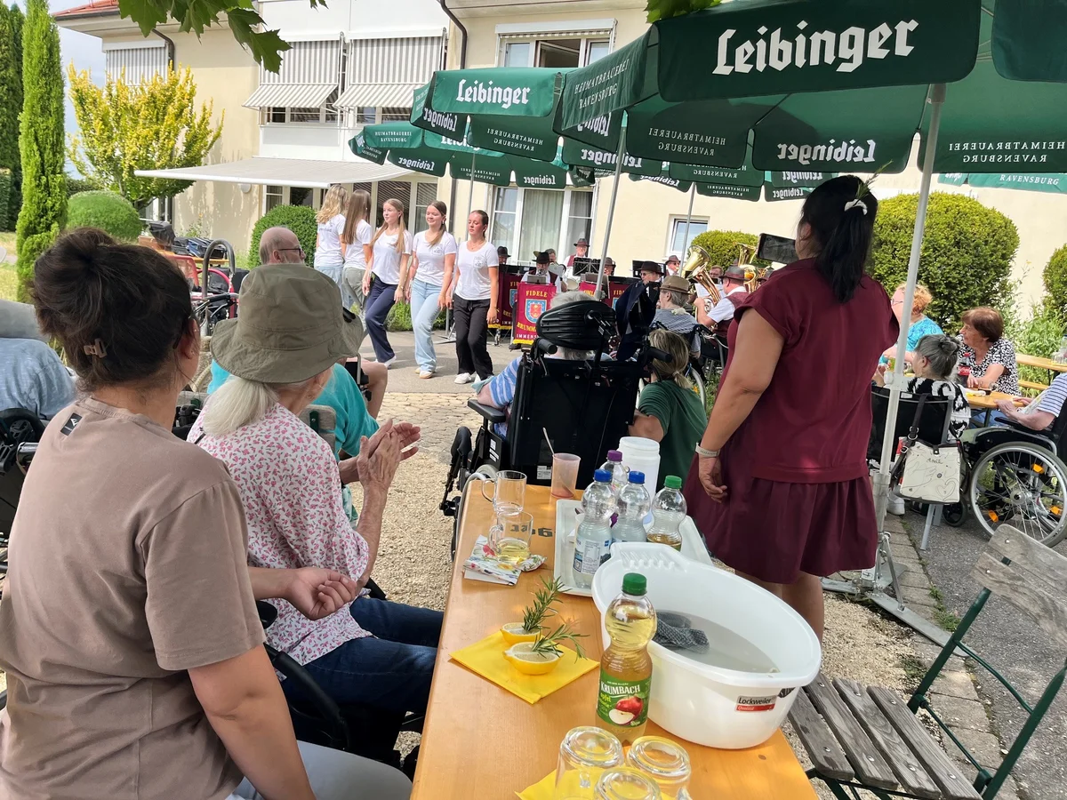 Im Hintergrund ist eine Tanzgruppe und im Vordergrund Zuschauerinnen und Zuschauer zu sehen.