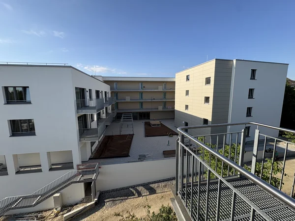 Ein neuer heller Gebäudekomplex in der Erstellung, mit einem silbernem Gestell im Vordergrund. 