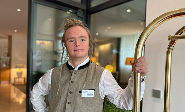 Ein Mann mit einer Weste steht im Eingangsbereich eines Hotels.