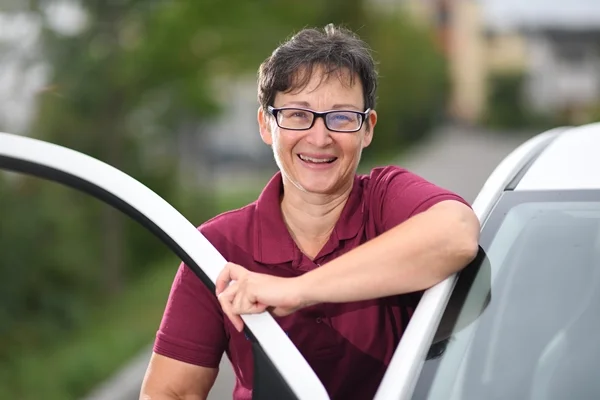 Das Bild zeigt eine Frau vor einer offenen Autotür
