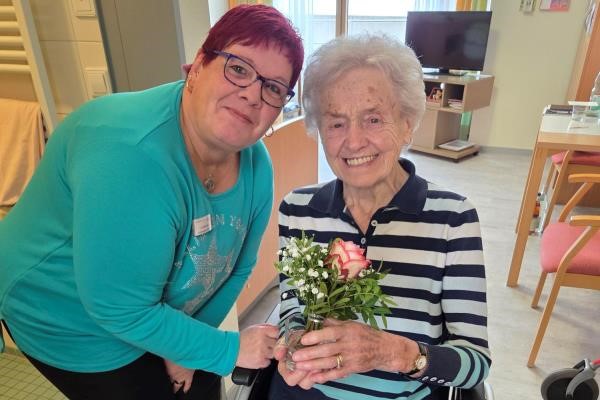 Das Bild zeigt zwei Frauen mit einer Rose