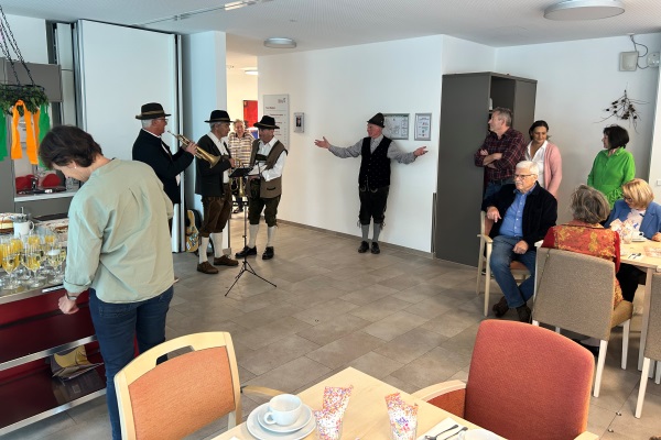 Das Bild zeigt eine Kapelle und Personen in einem Essraum