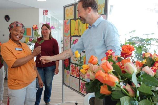 Das Bild zeigt einen Mann, der einer Frau eine Rose überreicht