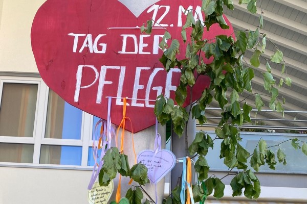 Das Bild zeigt ein Schilderherz zum Tag der Pflege an einer Laterne